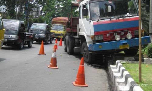 Rem blong, truk trailer bermuatan besi tabrak pembatas jalan