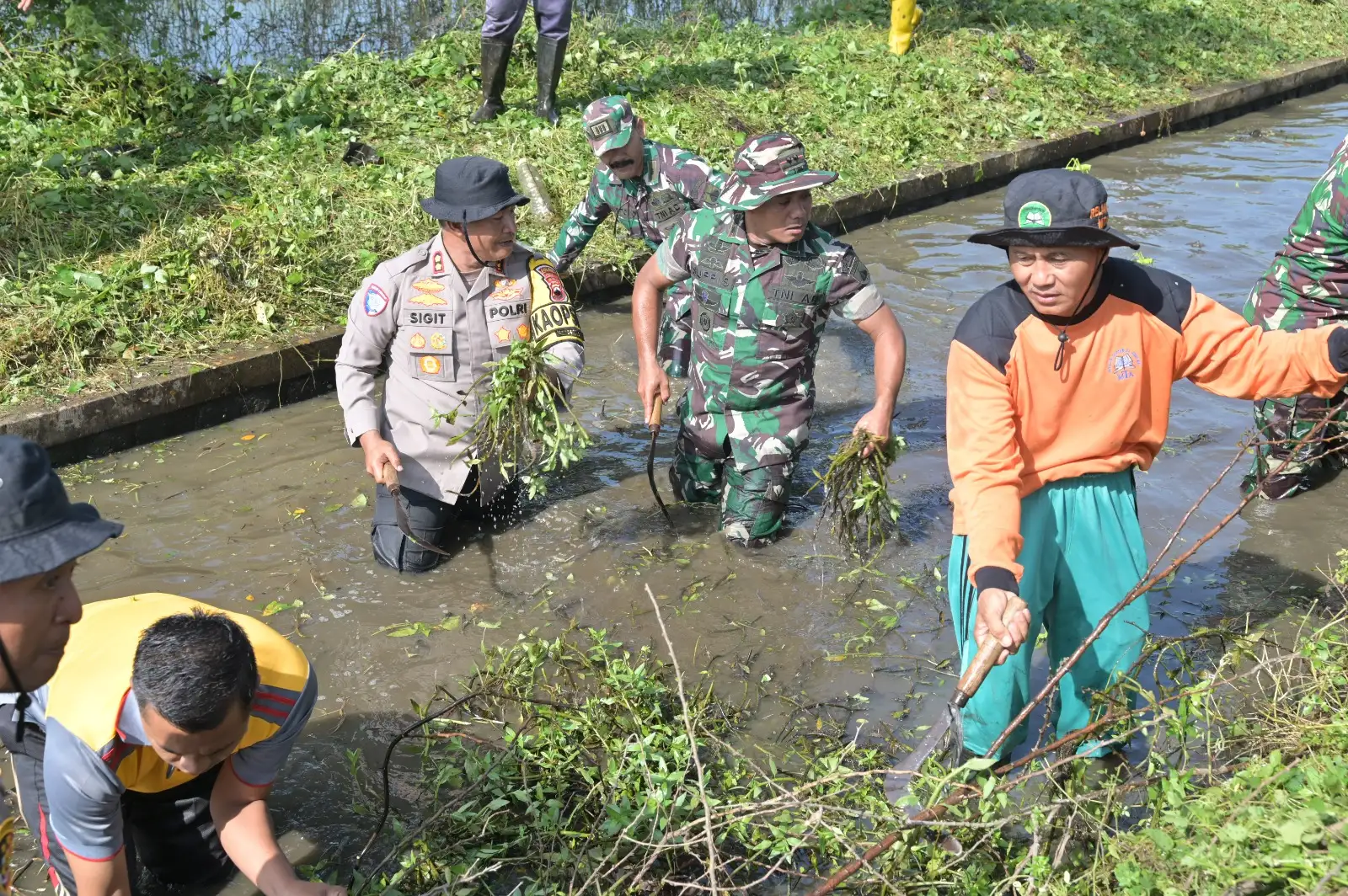 Anggota TNI-Polri Bersih-bersih Sampah di Saluran Irigasi Kriwen Sukoharjo